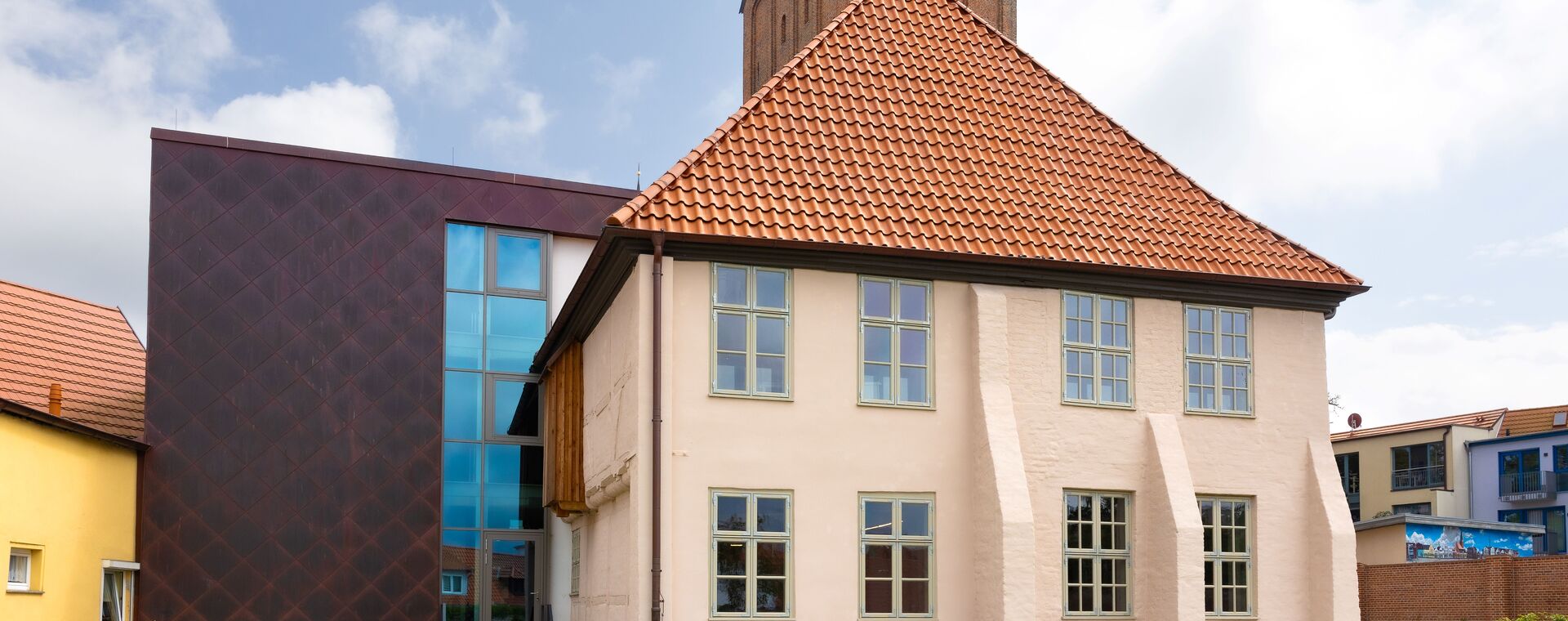 Ein Gebäude, der Papenhof im Hintergrund die Kirche.